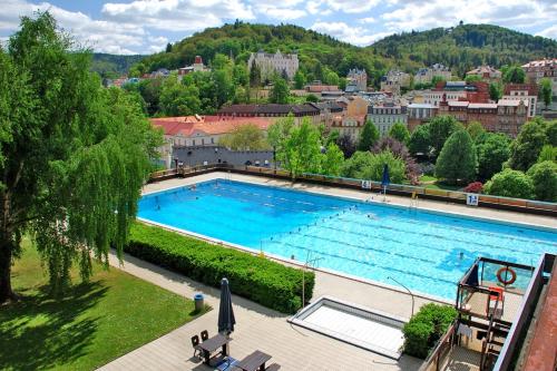 卡罗维发利利兹登斯瑟托卡酒店的一个大游泳池,后面有一个城市