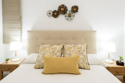马德里Apartamento con jardin privado y portero (A)的一张带两个枕头的白色床和墙上的时钟