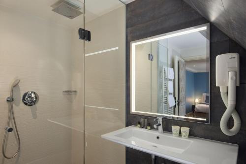 巴黎格兰德酒店的浴室配有盥洗盆和带镜子的淋浴