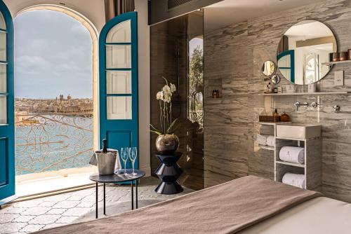 瓦莱塔Iniala Harbour House的一间带大窗户的卧室和一间浴室