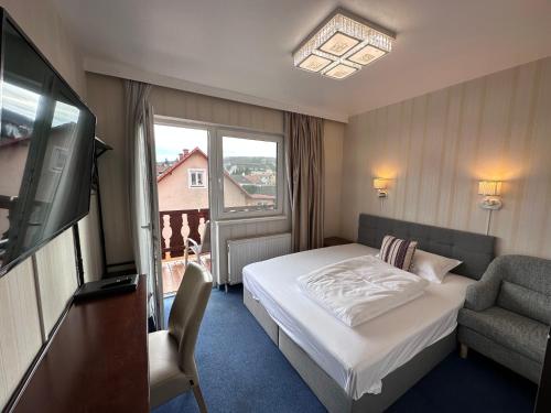 盖布利茨奥地利酒店的酒店客房配有一张床、一把椅子和一台电视。