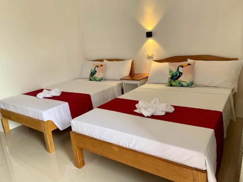 邦劳SUNSHINE STAY PANGLAO的一间设有两张红色和白色床单的房间