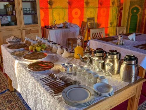 梅尔祖卡Erg chebbi Dunes Desert Camp的餐桌上放有食物盘子的桌子
