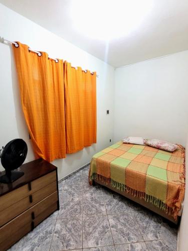 皮乌马Apartamento de 2 quartos的一间卧室配有床和橙色窗帘