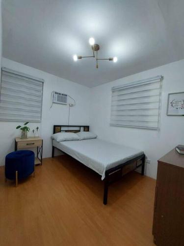 巴科洛德Cosy House in Bacolod City的一间卧室设有一张床和两个窗户。