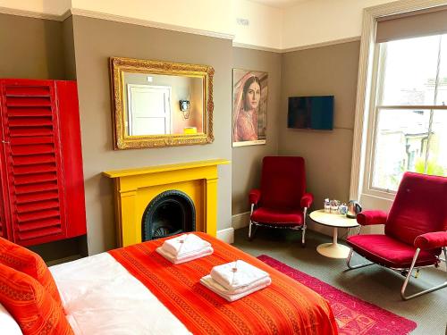 布莱顿霍夫睡眠旅馆的一间卧室配有一张床、两把椅子和一个壁炉