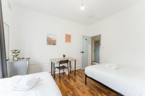 伦敦Upton Park Bedrooms 25 min to Central London的一间卧室配有两张床和一张桌子及椅子