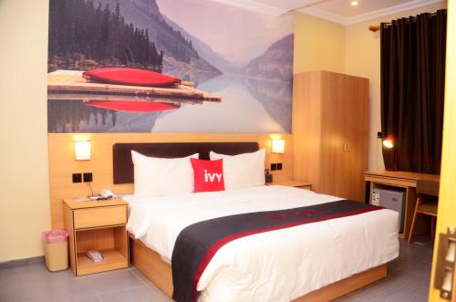 伊凯贾Ivy Hotel Emerald的酒店客房设有一张床,墙上挂有绘画作品