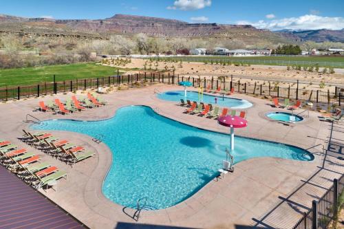 维尔京Fairfield Inn & Suites by Marriott Virgin Zion National Park的度假村的游泳池配有椅子和遮阳伞