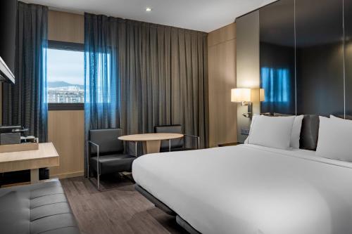 巴塞罗那桑茨万豪AC酒店的酒店客房带一张大床、一张桌子和椅子。