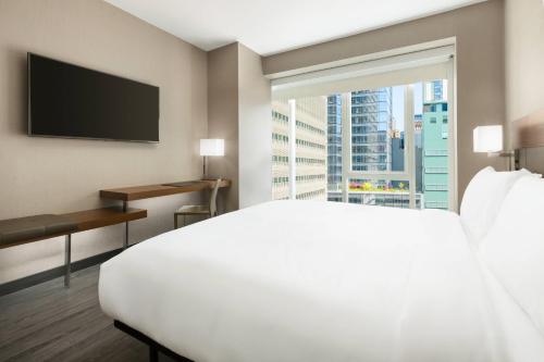 纽约纽约时报广场万豪AC酒店的酒店客房设有一张白色大床和一个窗户。