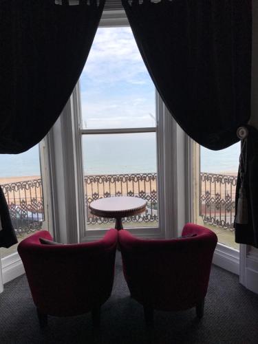 伊斯特布恩亚特兰大旅馆的一间设有两把椅子、一张桌子和一个窗户的房间