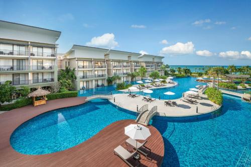 蔻立Le Meridien Khao Lak Resort & Spa的一张带椅子和遮阳伞的度假村游泳池的图片