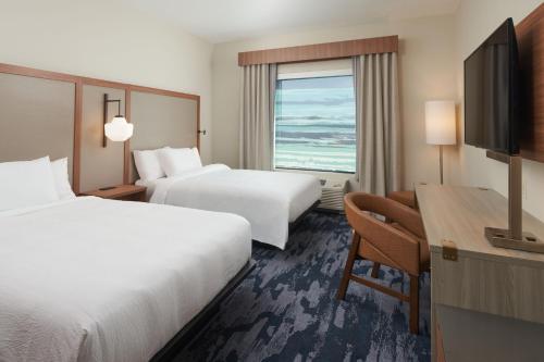 西棕榈滩Fairfield by Marriott Inn & Suites West Palm Beach的酒店客房设有两张床、一张桌子和一台电视。