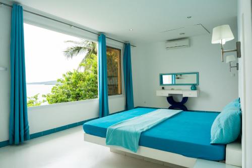 迭戈苏瓦雷斯villa piscine à louer a DIEGO SUAREZ. MADAGASCAR的一间卧室设有蓝色的床和大窗户