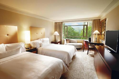 首尔Westin Josun Seoul Hotel的酒店客房设有两张床和一台平面电视。