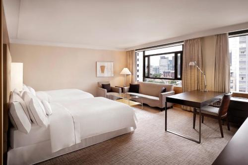 首尔Westin Josun Seoul Hotel的一间酒店客房,配有一张白色的床和一张书桌