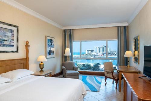 迪拜喜来登朱美拉海滩度假酒店的配有一张床、一张书桌和一扇窗户的酒店客房