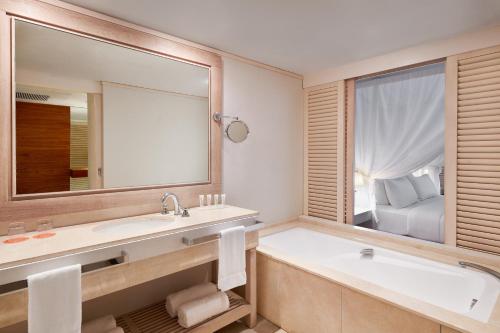 Oro Bay松林岛子午线度假酒店的一间带浴缸和大镜子的浴室