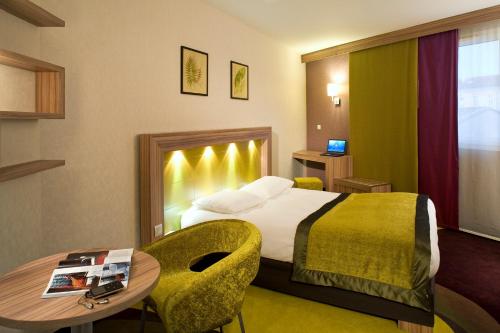 利布尔讷利布尔讷圣艾米隆美居酒店的酒店客房配有一张床铺和一张桌子。