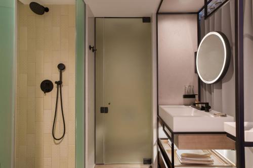 皇后区Renaissance New York Flushing Hotel at Tangram的带淋浴、盥洗盆和镜子的浴室