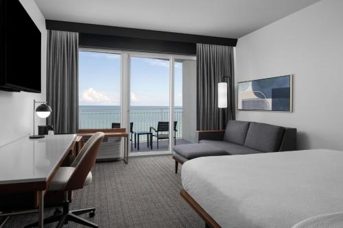 默特尔比奇Courtyard by Marriott Myrtle Beach Oceanfront的酒店客房设有一张床和一张书桌,还有一间享有美景的客房。