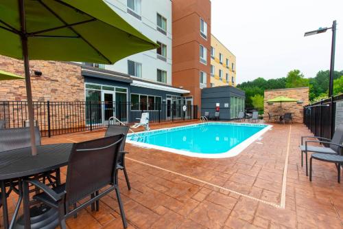 伍德斯托克Fairfield Inn & Suites by Marriott Atlanta Woodstock的一个带桌椅和遮阳伞的游泳池