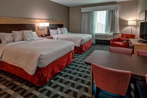 温泉城TownePlace Suites by Marriott Hot Springs的酒店客房设有两张床和一张桌子。