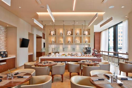 德梅因AC Hotel by Marriott Des Moines East Village的餐厅设有桌椅和大窗户。