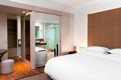 布拉伊新喀里多尼亚喜来登德瓦Spa及高尔夫度假酒店的一间卧室配有一张床,浴室设有浴缸