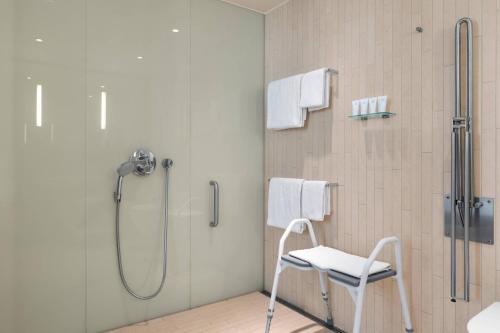 哥本哈根哥本哈根贝拉天空万豪AC酒店的浴室内配有带白色椅子的淋浴