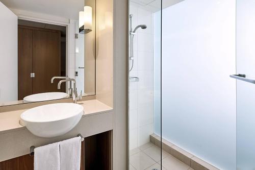悉尼悉尼北莱德万怡酒店的一间带水槽和玻璃淋浴的浴室