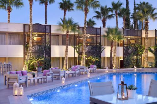 安曼安曼万豪酒店的酒店游泳池设有桌椅,并种植了棕榈树。
