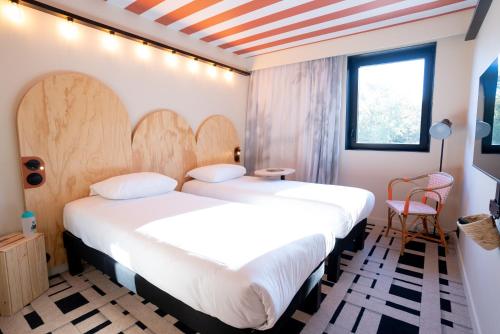 蒙托邦ibis Styles Montauban的酒店客房设有两张床和窗户。