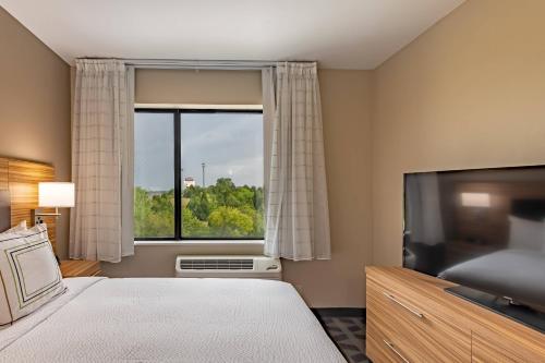 梅斯基特TownePlace Suites by Marriott Dallas Mesquite的一间带大窗户和电视的卧室