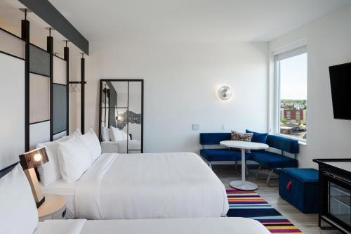 哥伦布Aloft Columbus的一间酒店客房,设有两张床、一张桌子和一台电视机