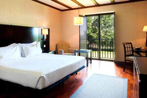 巴利亚多利德圣安娜帕拉西奥生活方式万豪AC酒店的一间带大床的卧室和一个阳台