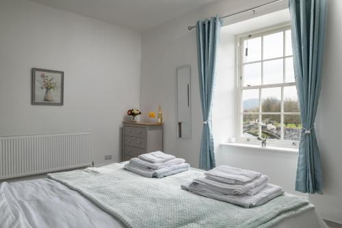 兰鲁斯特Glan Conwy House One and Two Bedroom Apartments的白色卧室,配有带毛巾的床
