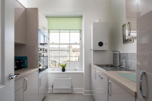兰鲁斯特Glan Conwy House One and Two Bedroom Apartments的白色的厨房设有水槽和窗户