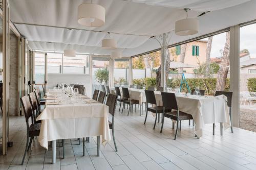 马里纳-迪-皮特拉桑塔米尔顿酒店 的餐厅设有白色的桌椅和窗户。
