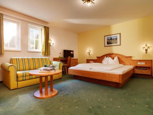 StrengenPosthotel Strengen am Arlberg的一间卧室配有一张床、一张沙发和一张桌子