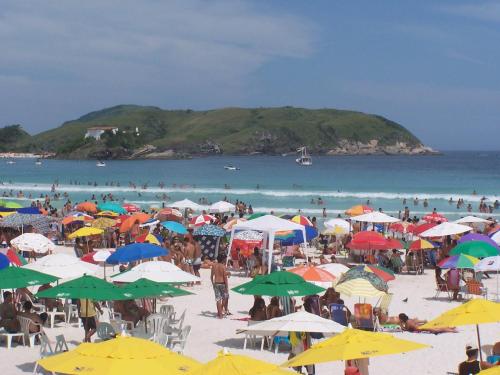 卡波布里奥Zênit Hostel da Cris的海滩上一群人拿着遮阳伞