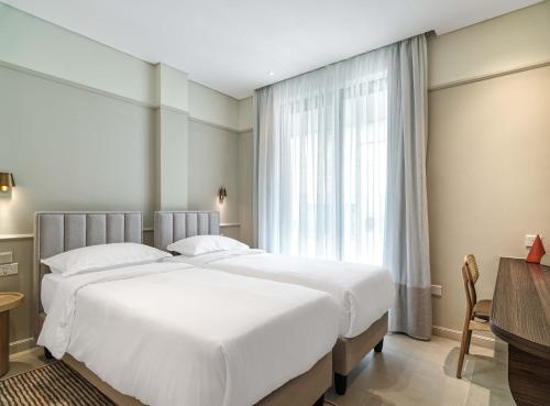 拉纳卡LIV Mackenzie Beach Suites Larnaca ADULTS ONLY的酒店客房设有两张床和窗户。