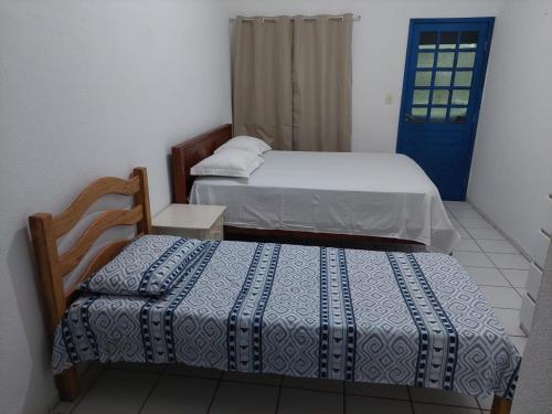 塔曼达雷CASA DA NINA的一间卧室设有两张床和一扇蓝色的门