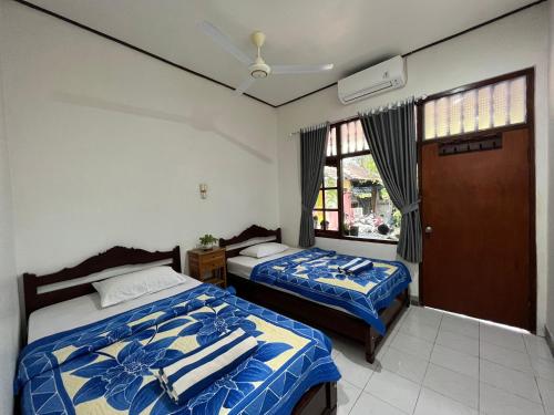 八丹拜Bagus Homestay的一间卧室设有两张床和窗户。
