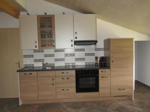 Le Noirmontschöner Aufenthalt的厨房配有木制橱柜和炉灶烤箱。