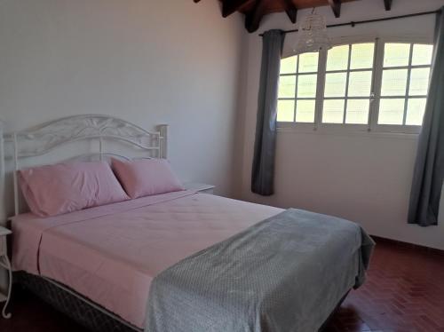 AreguáCasa de la Amistad的一间卧室配有带粉红色枕头的床和窗户。