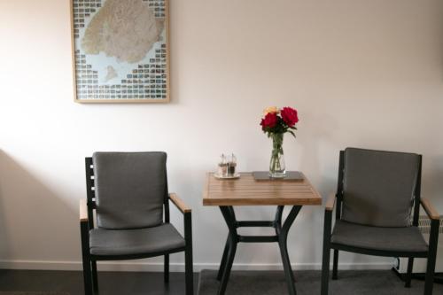 瓦纳卡Wanaka Lake Studio (New)的两把椅子和一张带花瓶的桌子