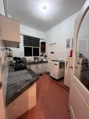 瓜埠RUMAH SINGGAH APARTMENT的厨房配有白色家电和红色瓷砖地板。