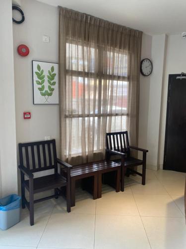 古晋D'Green Hotel Kuching的一间带两把椅子和一张桌子的用餐室以及窗户。
